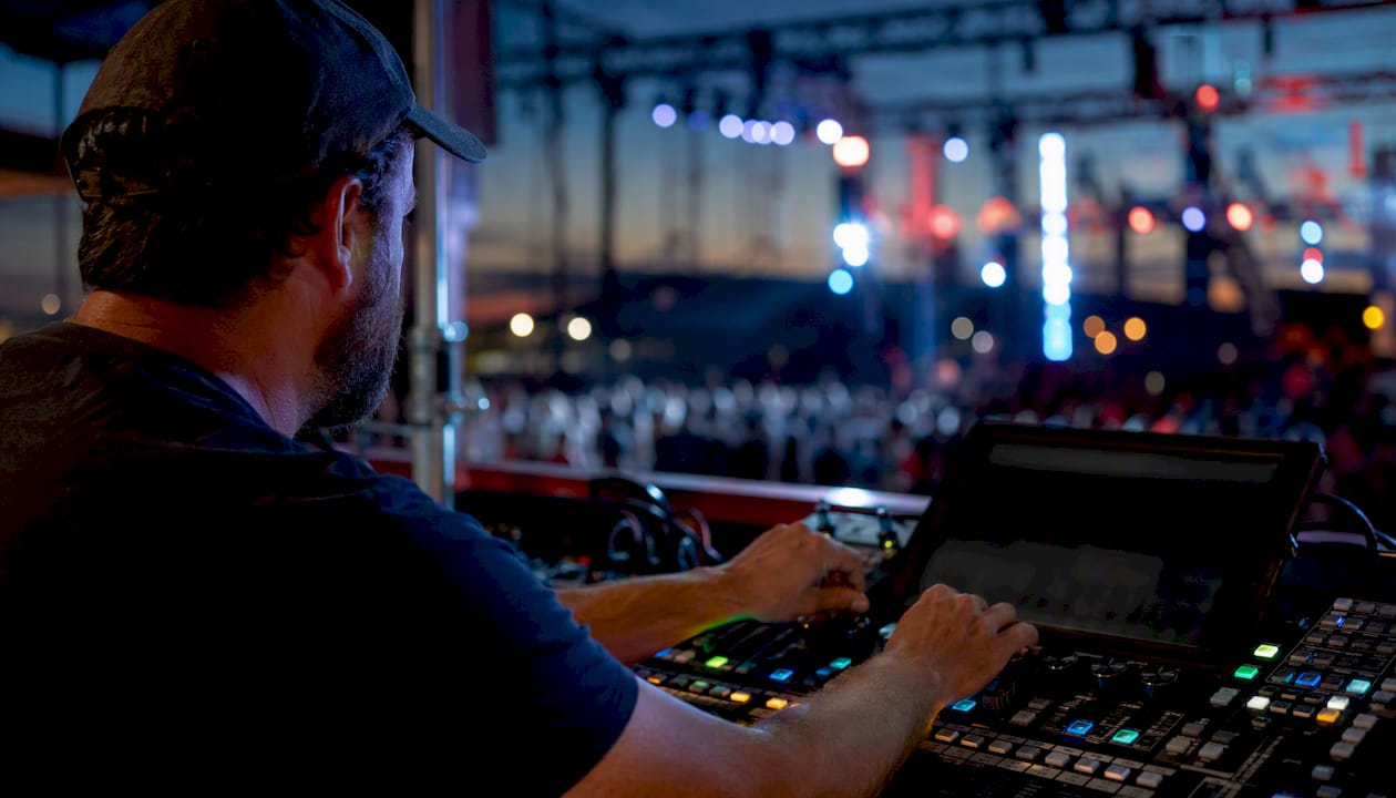 Hands adjusting lighting console amid flicker